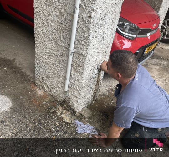 אדם עובד על צינור ליד עמוד בטון